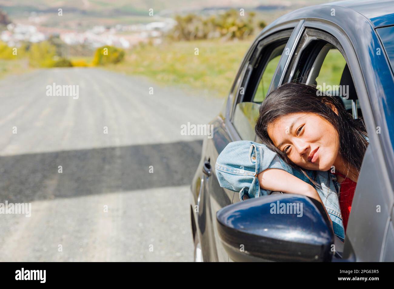 Lächelnde asiatische Frau schaut aus Auto Stockfoto