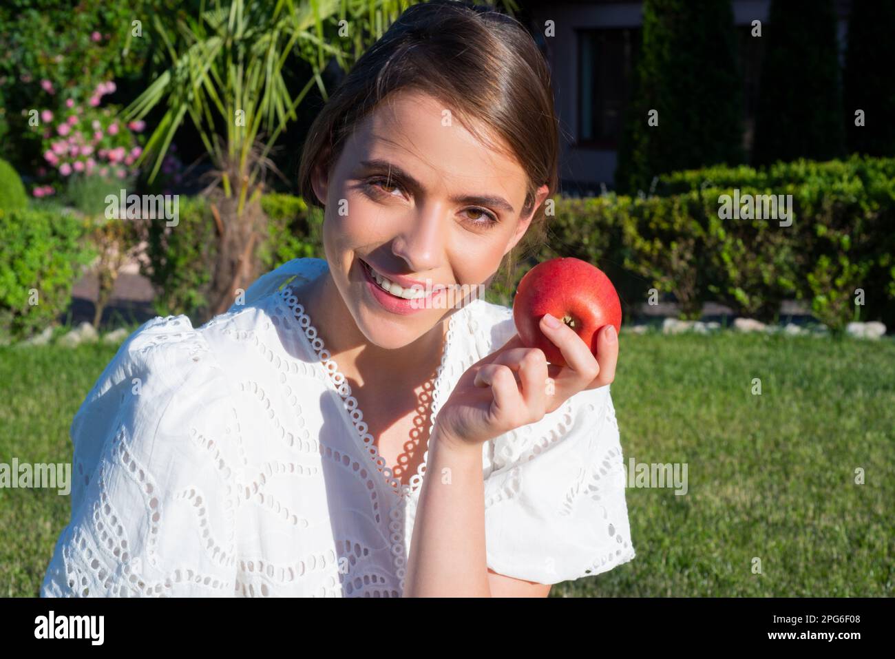 Menschen mit Apfel. Porträt einer glücklichen lächelnden Frau, die Apfel im Park isst. Gesunde Apfelfrucht für natürliche Vitamine, Ernährung und gesunde Lebensweise Stockfoto