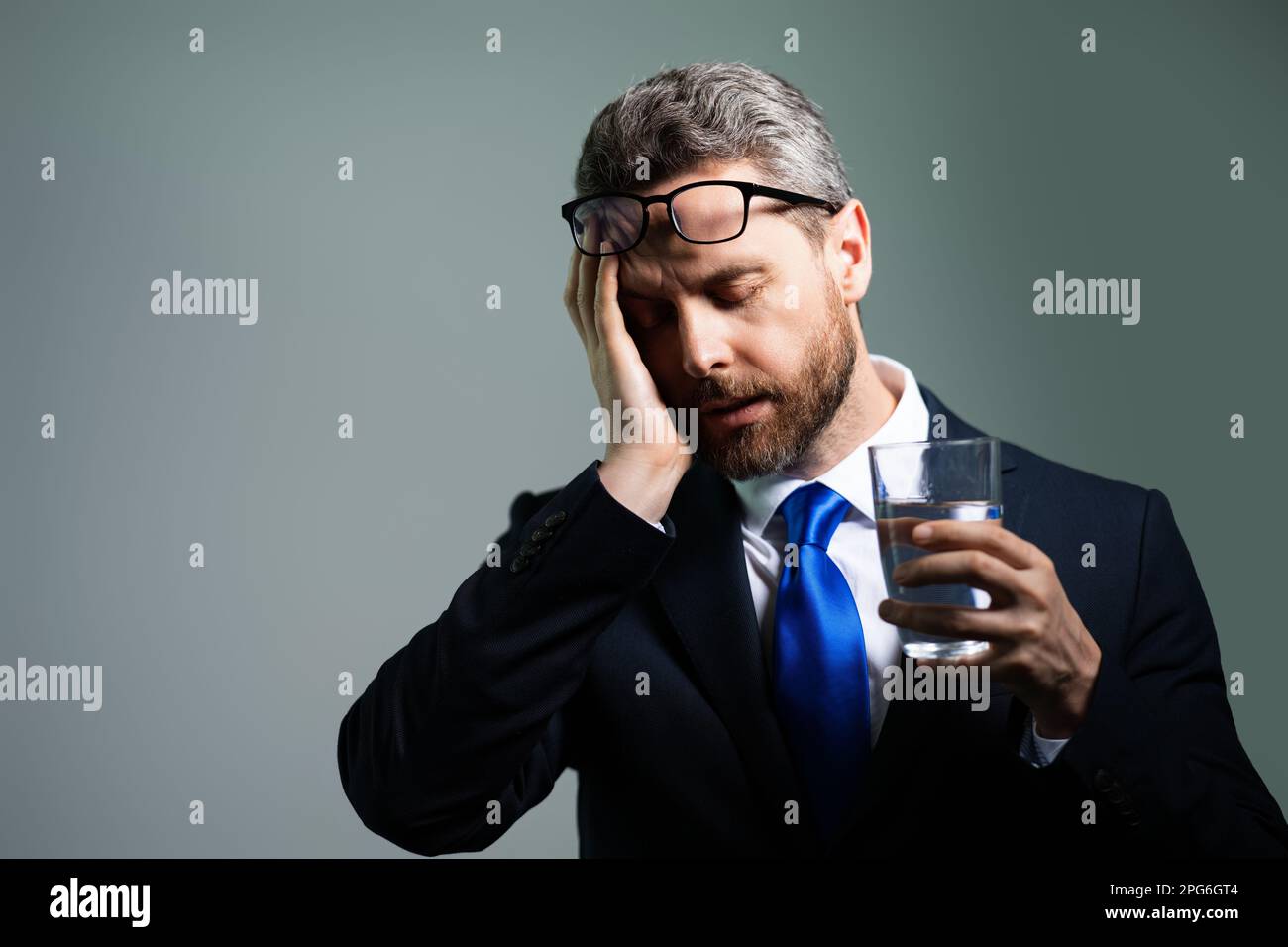 Ein müder Mann, der schreckliche Kopfschmerzen hat. Erschöpfter Mann fühlt sich ungesund, verärgert über Kopfschmerzen Krankheit. Gestresster Mann mittleren Alters mit isoliertem Kopfschmerz Stockfoto