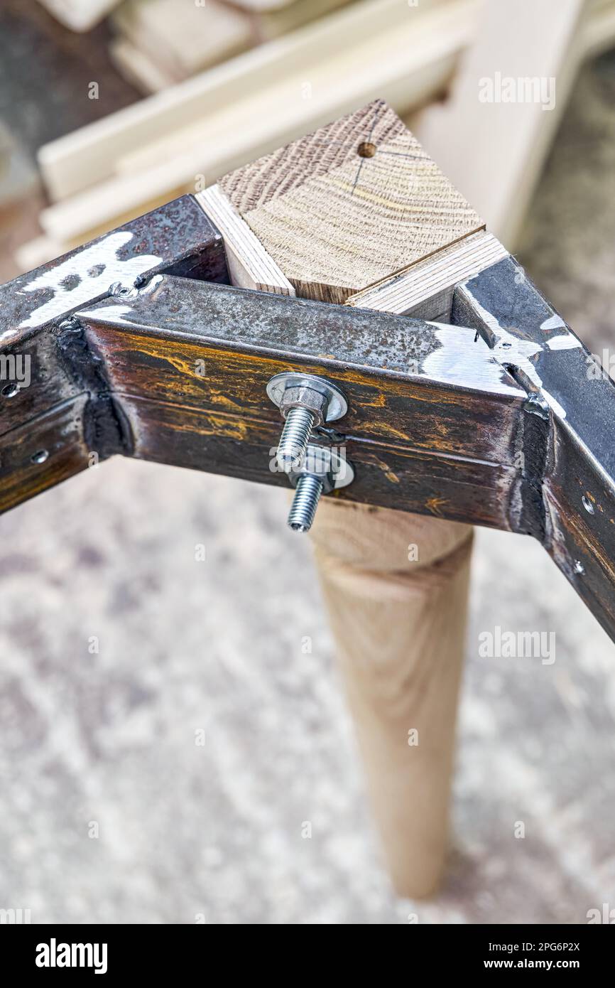 Holzschnittiger Schenkel aus massiver Eiche mit Metalltischrahmen während des Herstellungsprozesses des Esstisches in der Werkstattnahansicht Stockfoto