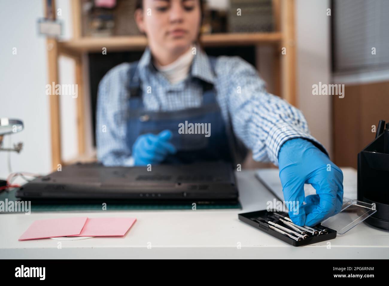 Techniker repariert einen beschädigten Laptop-Notebook-Computer mit einem Schraubendreher. Lösen Sie zur Reparatur die Schrauben aus dem Laptop-Gehäuse mit einem Schraubendreher Stockfoto