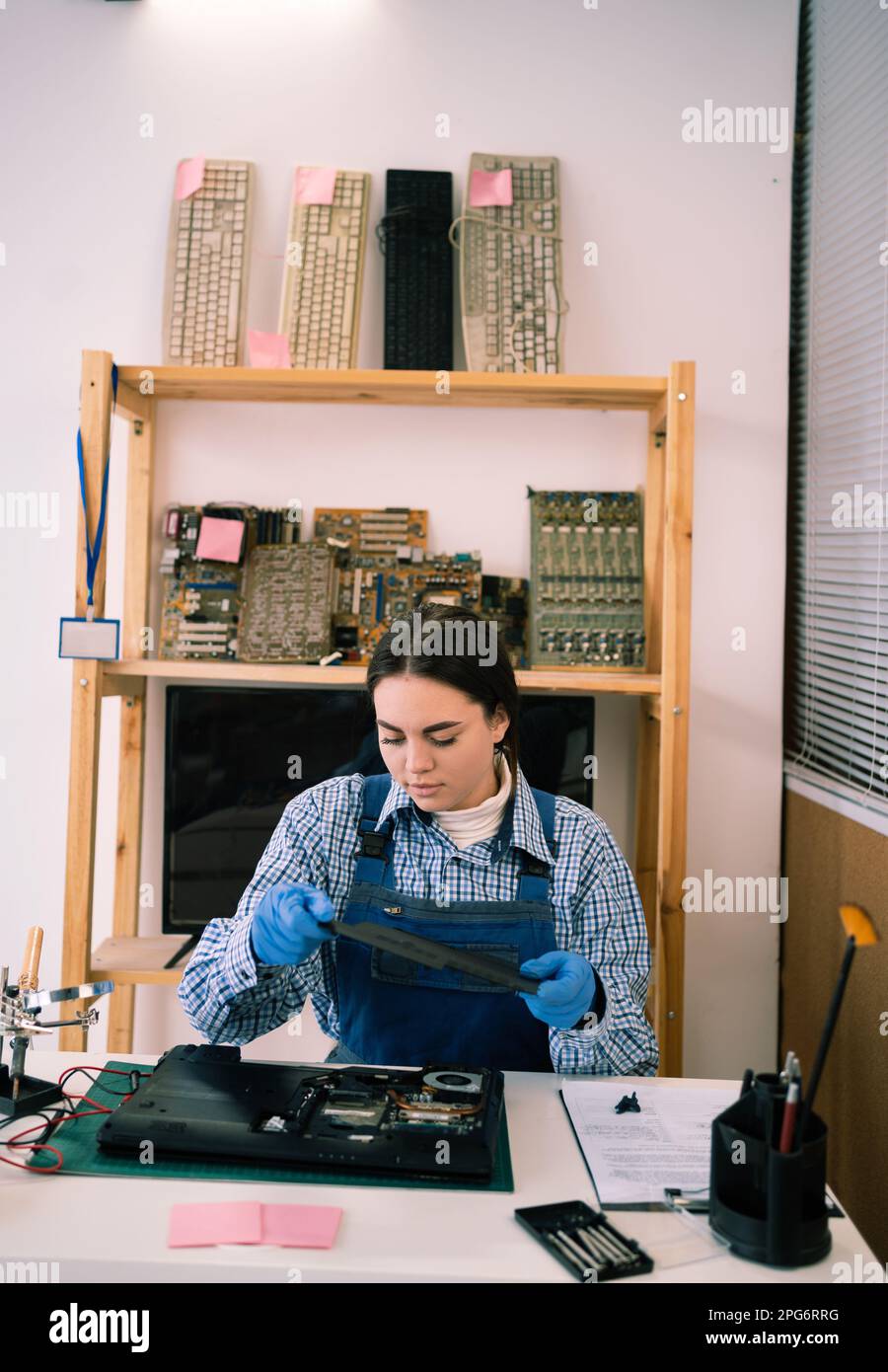 Demontage des Laptops in einer elektronischen Reparaturwerkstatt oder Werkstatt. Eine Ingenieurin, die das Laptop-Gehäuse trennt. Elektronische Renovierung, Geschäft, Beruf Stockfoto