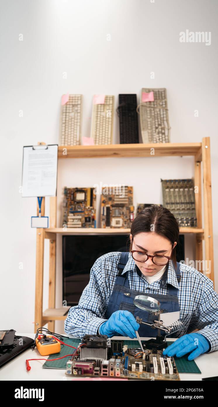 Reparatur der Hauptplatine im Service-Center. Computertechnikerin, die Computerteile testet. Stockfoto