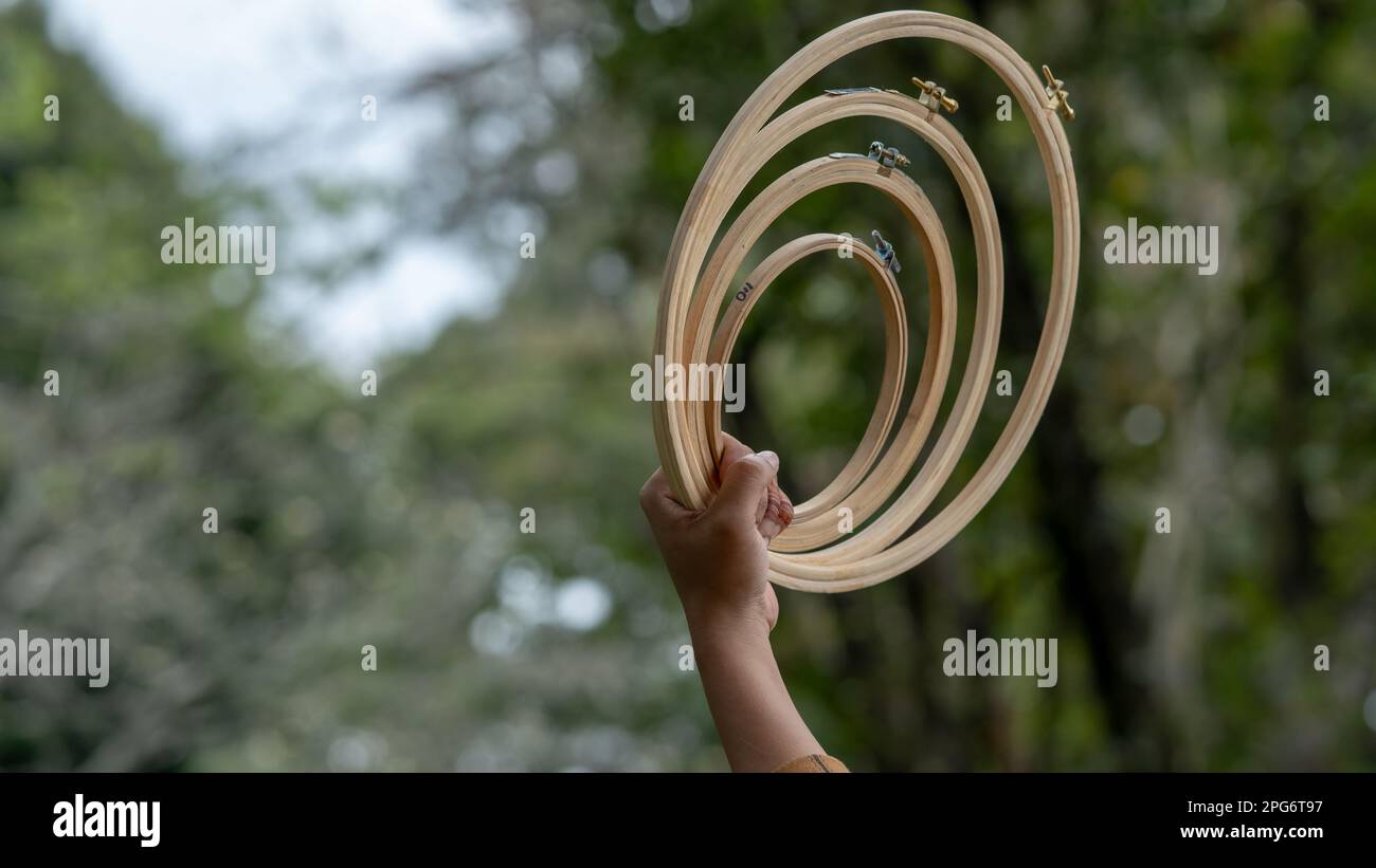 Eine Frau, die einen Holzrahmen hält und durch die Reifen in den Garten schaut. Stockfoto