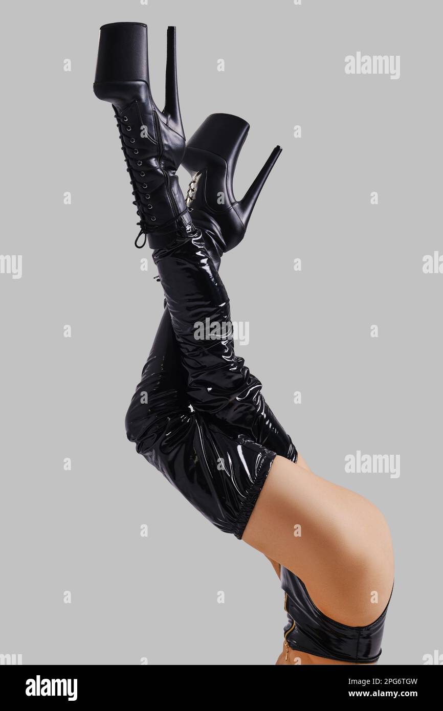 Hochgezogene weibliche Beine in Stangentanzstiefeln auf grauem Hintergrund Stockfoto
