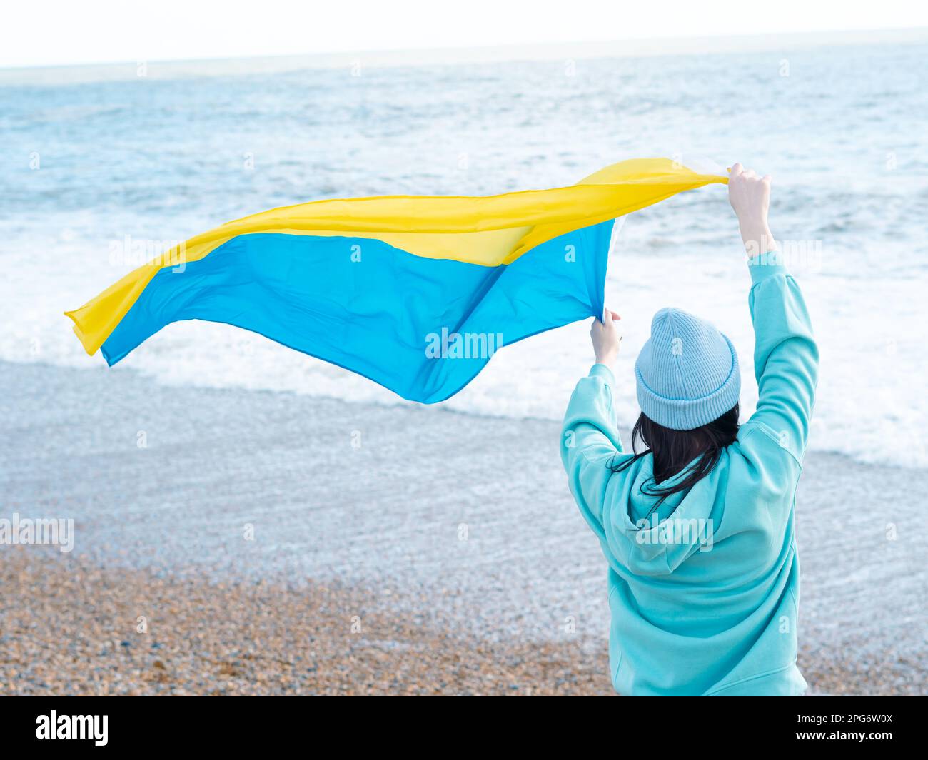 Braune Frau in blauem Hoodie und blauem Hut mit ukrainischer Nationalflagge, patriotisches Konzept Stockfoto