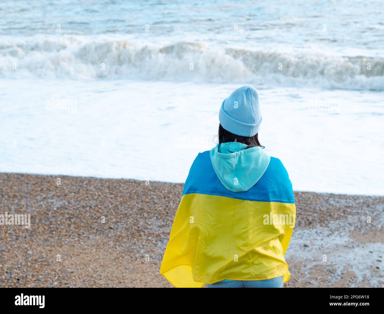 Braune Frau in blauem Hoodie und blauem Hut mit ukrainischer Nationalflagge, patriotisches Konzept Stockfoto