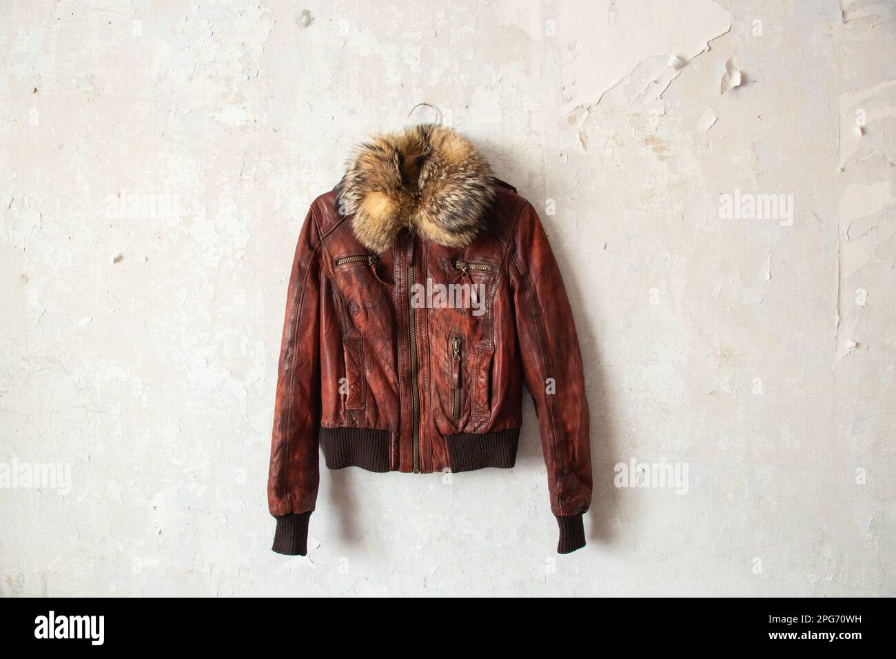 Winterjacke aus rotem Pelzleder, die an einem Kleiderbügel an einer weißen Wand hängt Stockfoto