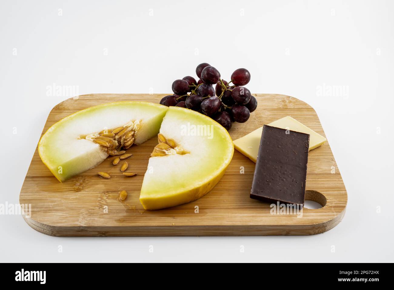 Nach dem Abendessen gibt es frische Honigtau-Melonenscheiben mit Trauben und weißer und dunkler Schokolade, isoliert auf weißem Hintergrund Stockfoto Nach dem Abendessen gibt es frische Honigtau-Melonenscheiben mit Trauben und weißer und dunkler Schokolade, isoliert auf weißem Hintergrund Stockfoto