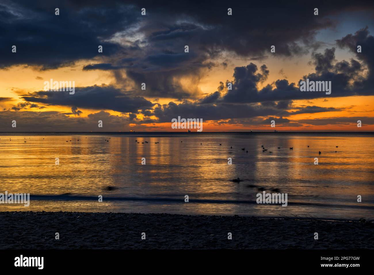 Malerischer Sonnenaufgang an der Ostsee mit stürmischen Wolken am Himmel und Reflexion des Sonnenlichts im Wasser, Nordpolen. Stockfoto