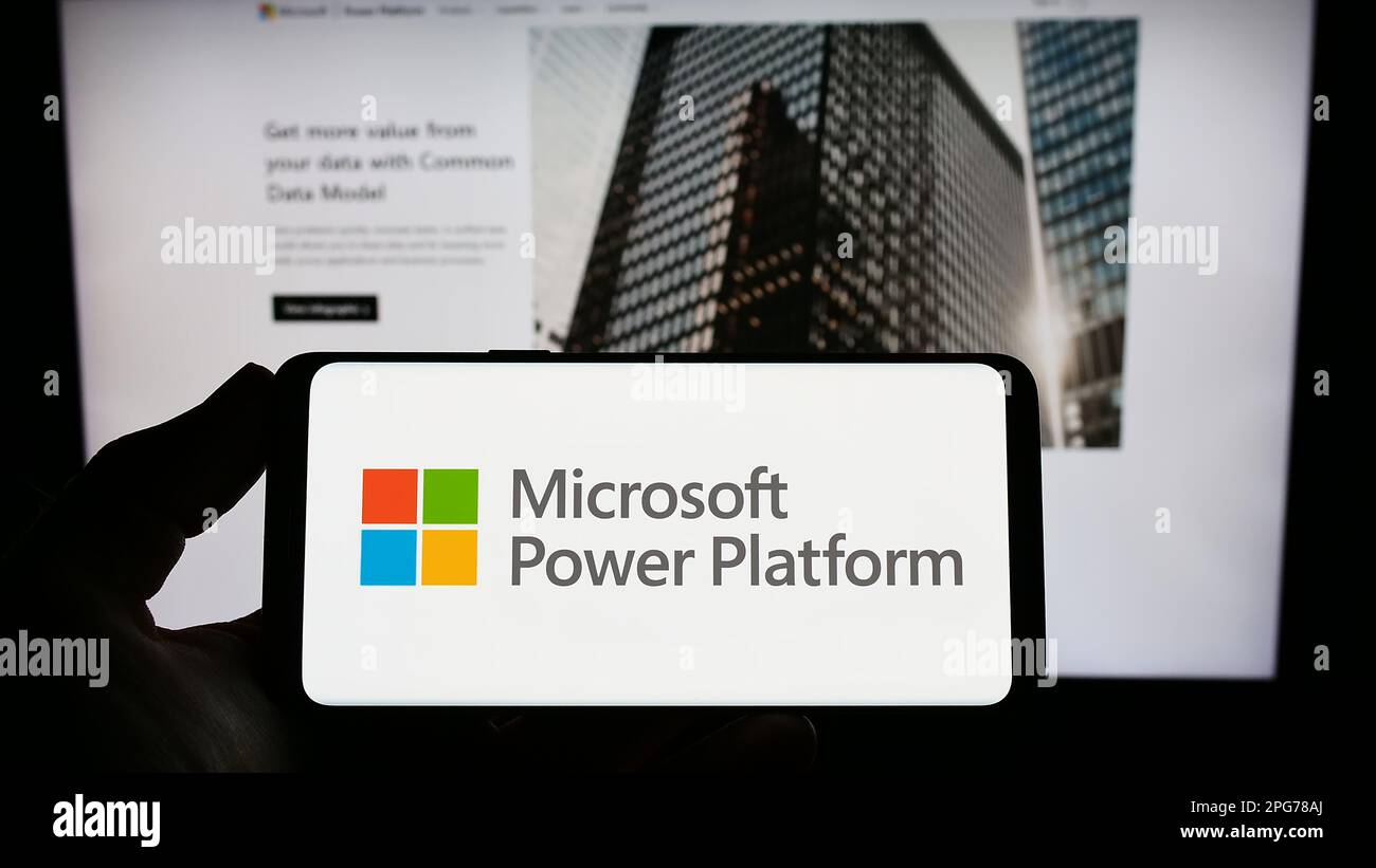 Person, die ein Smartphone mit dem Logo der Softwareanwendung Microsoft Power Platform auf dem Bildschirm vor der Website hält. Konzentrieren Sie sich auf das Display des Telefons. Stockfoto