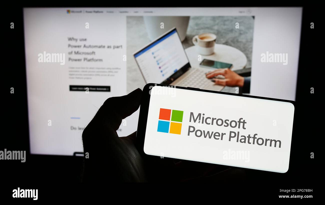Person, die ein Mobiltelefon mit dem Logo der Softwareanwendung Microsoft Power Platform auf dem Bildschirm vor der Webseite hält. Konzentrieren Sie sich auf das Display des Telefons. Stockfoto