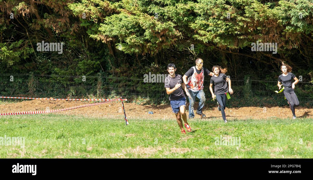 Bei einer Zombie-Evakuierung laufen Spaßsuchende um einen Angriffskurs, während sie versuchen, Zombies zu vermeiden, wie es für Norfolk normal ist. Stockfoto