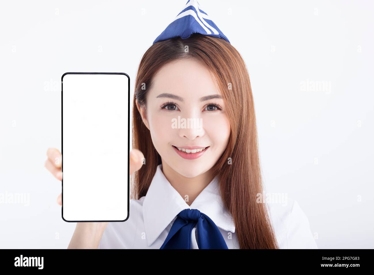 Wunderschöne Stewardess der Fluggesellschaft, die das Mobiltelefon mit leerem Bildschirm auf weißem Hintergrund zeigt Stockfoto