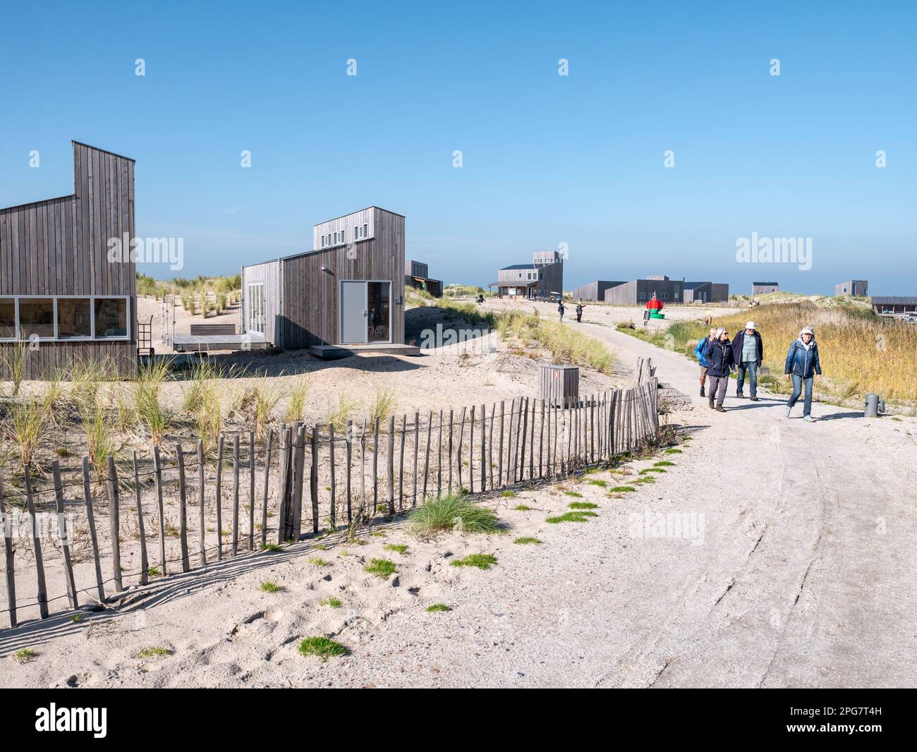Menschen, die auf Fußwegen und nachhaltigen hölzernen Ferienhäusern auf der Insel Marker Wadden, Niederlande, spazieren Stockfoto