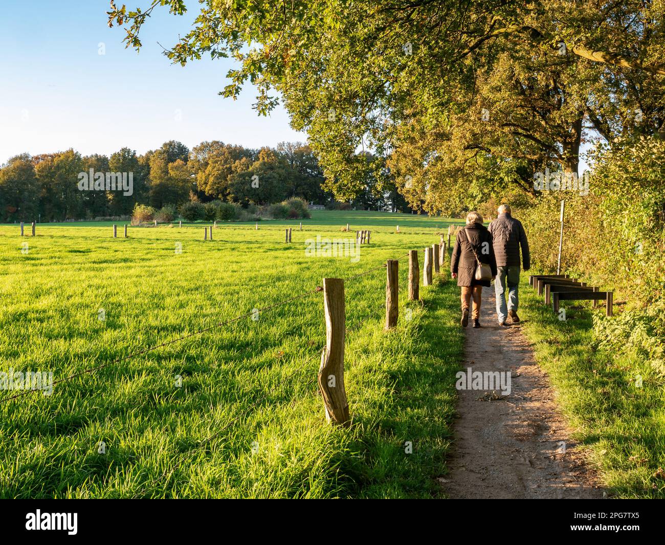 Ein älteres Paar, das auf einem Fußweg durch die Natur in der Nähe der Stadt Ootmarsum, Overijssel, Niederlande, spaziert Stockfoto