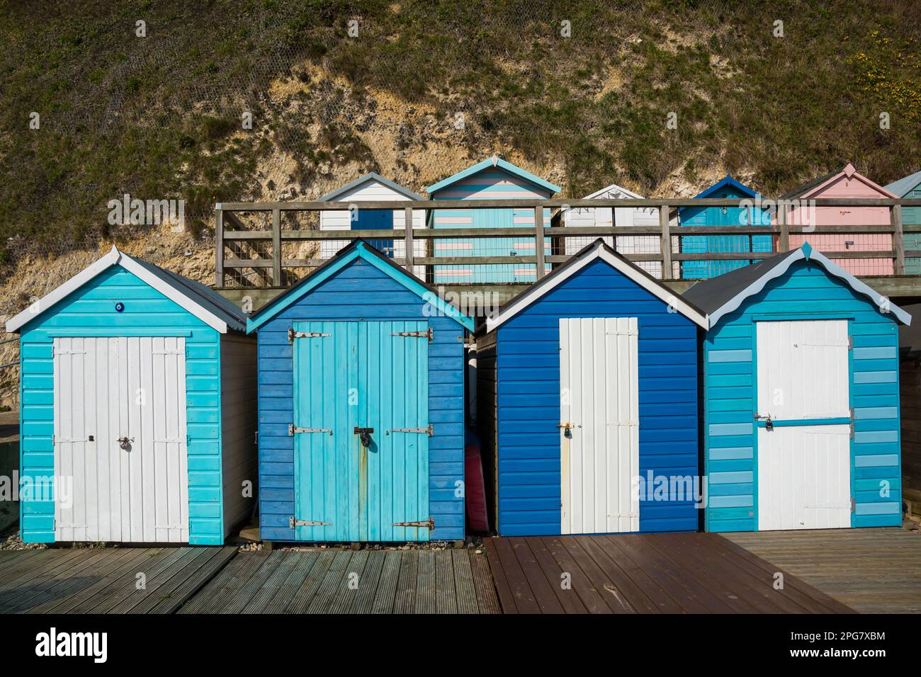 Reihen blauer Strandhütten am Fuß der Klippen am Beer Beach, Seaton, Devon UK im März Stockfoto