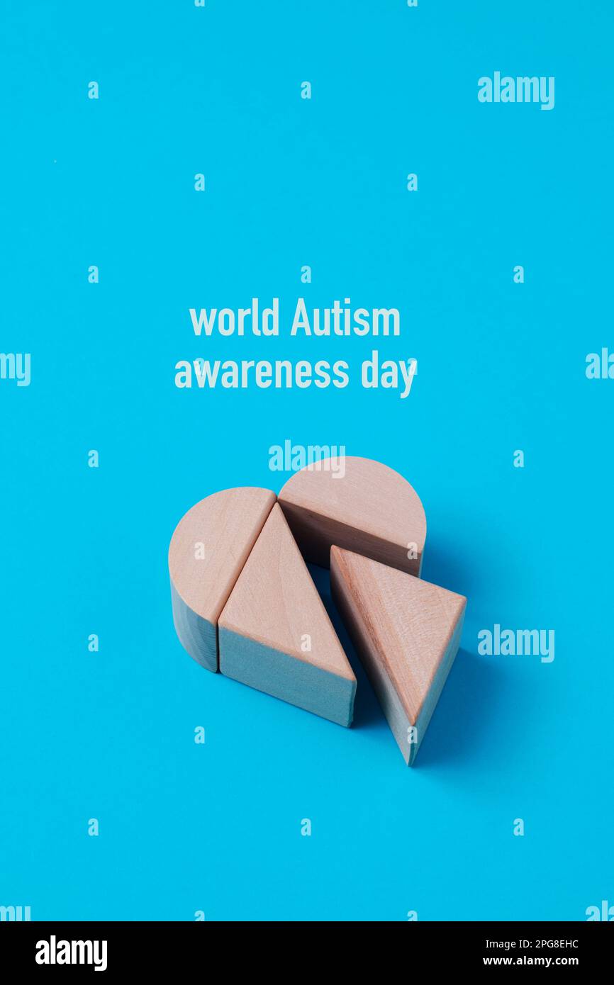 Nahaufnahme einiger Bausteine, die ein Herz bilden, und des Text World Autismus Awareness Day vor blauem Hintergrund Stockfoto