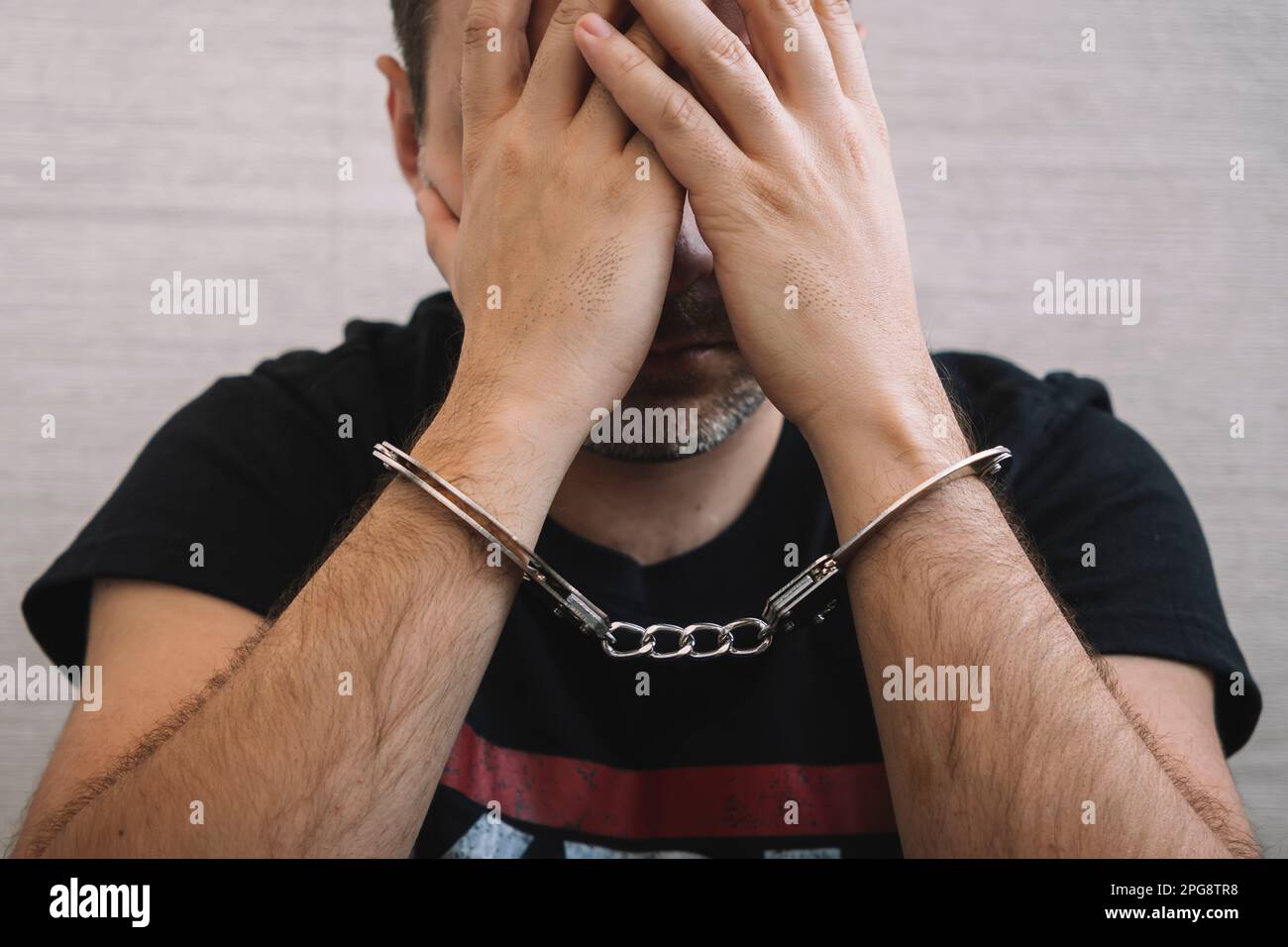 Festgenommener Mann mit Handschellen. Ein Verbrecher in Handschellen bedauert das Verbrechen. Stockfoto
