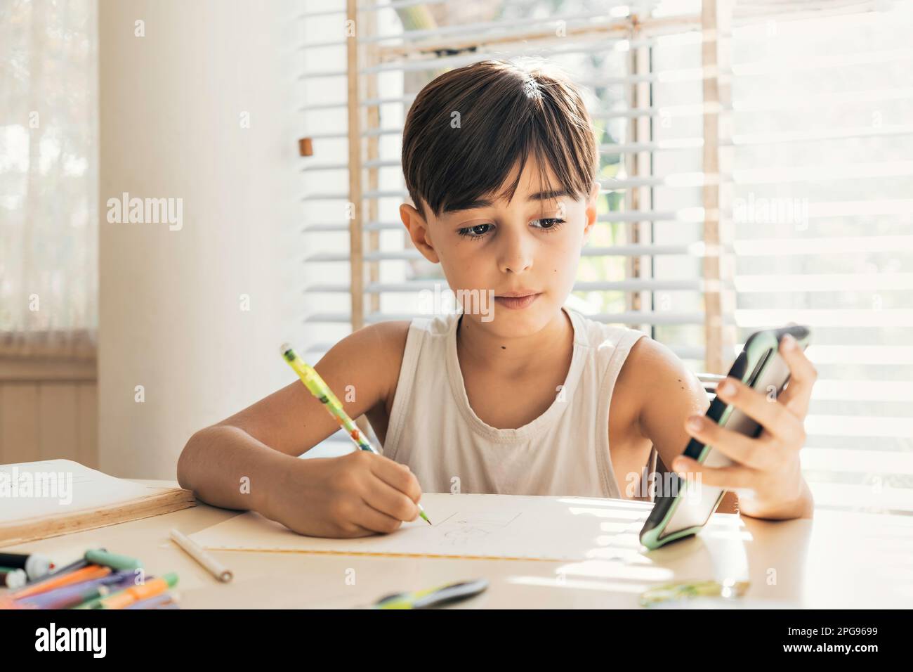 Kindersitz zu Hause mit Stift in der Hand zeichnen und ausmalen. Lernprozess und kreative Entwicklung von Kindern. Stockfoto
