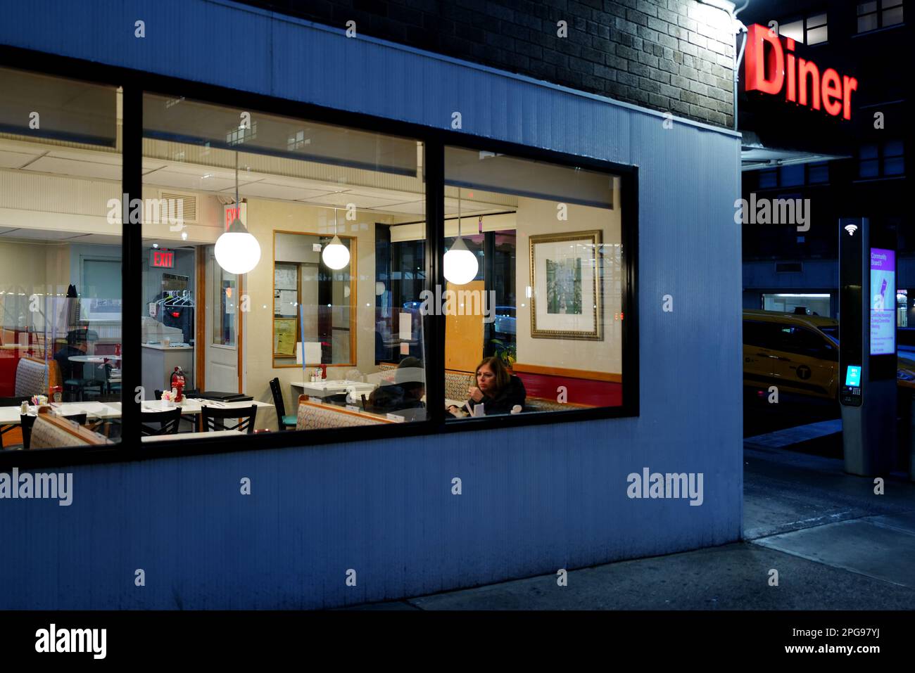 Eine Frau in einem New York City Diner bei Nacht Stockfoto