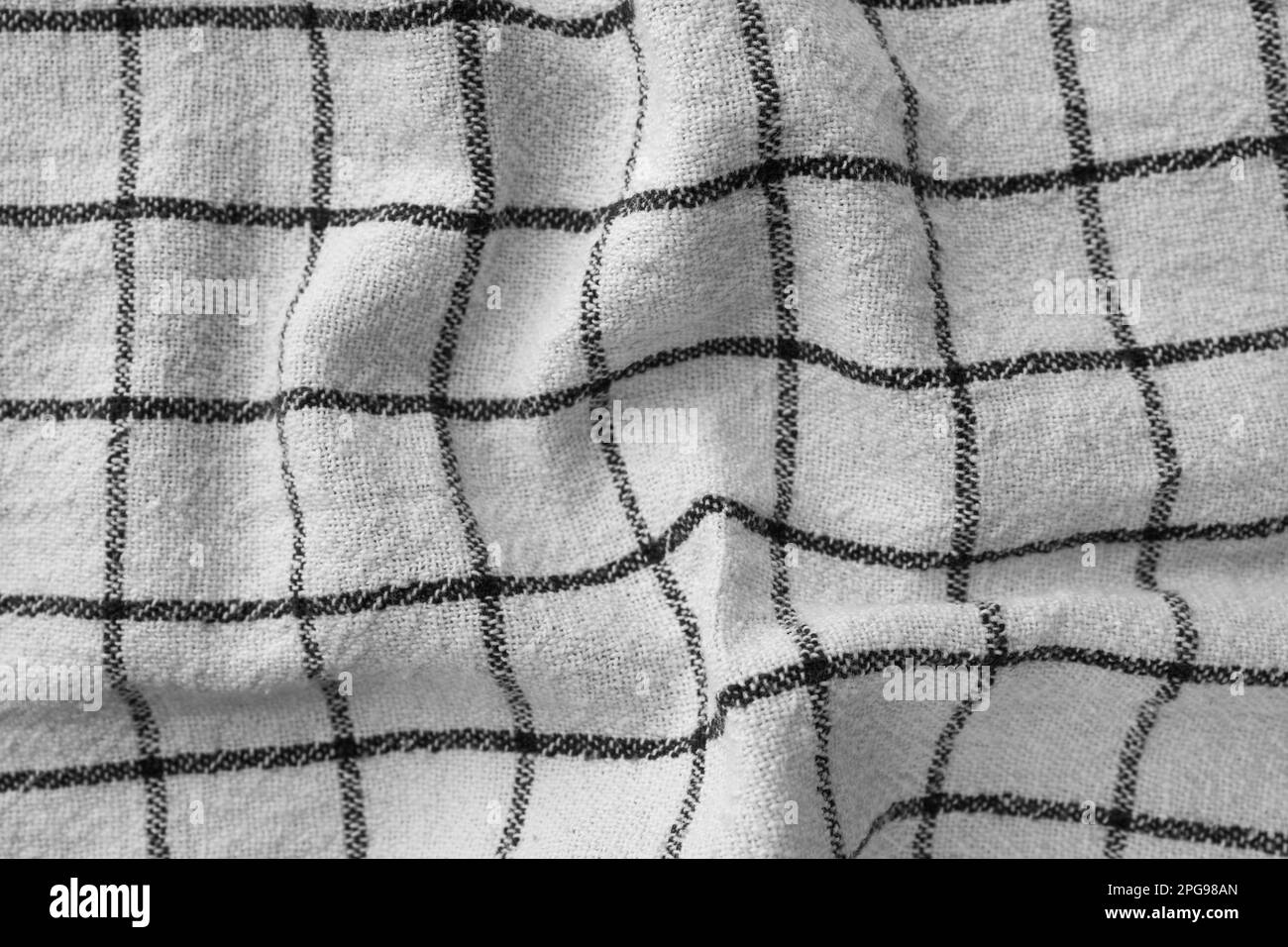Klassisches Küchenhandtuch mit Karomuster in Schwarz und Weiß. Zerknitterter Textilhintergrund mit sichtbarem Gewebe- und Fadendetail. Ideal für Web- und Druckanwendungen Stockfoto