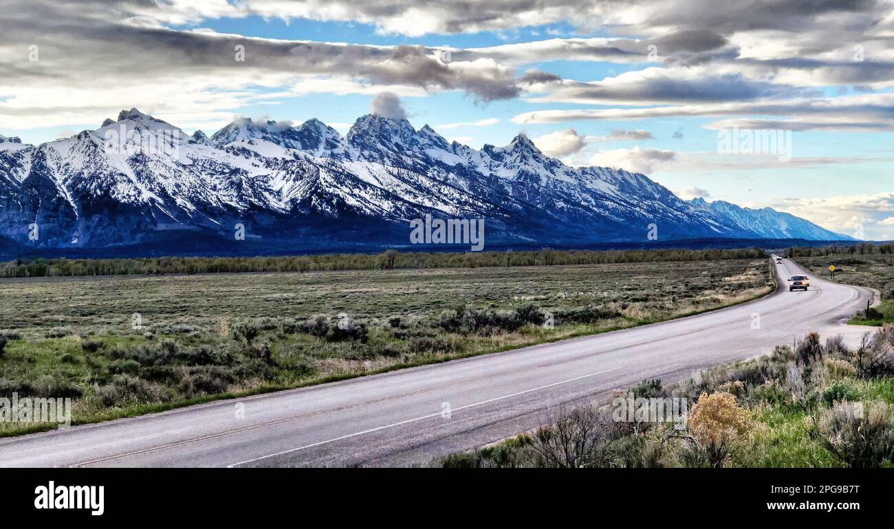 Herrlicher Blick auf eine offene Landstraße an einem sonnigen Tag mit atemberaubender Berglandschaft im Hintergrund Stockfoto