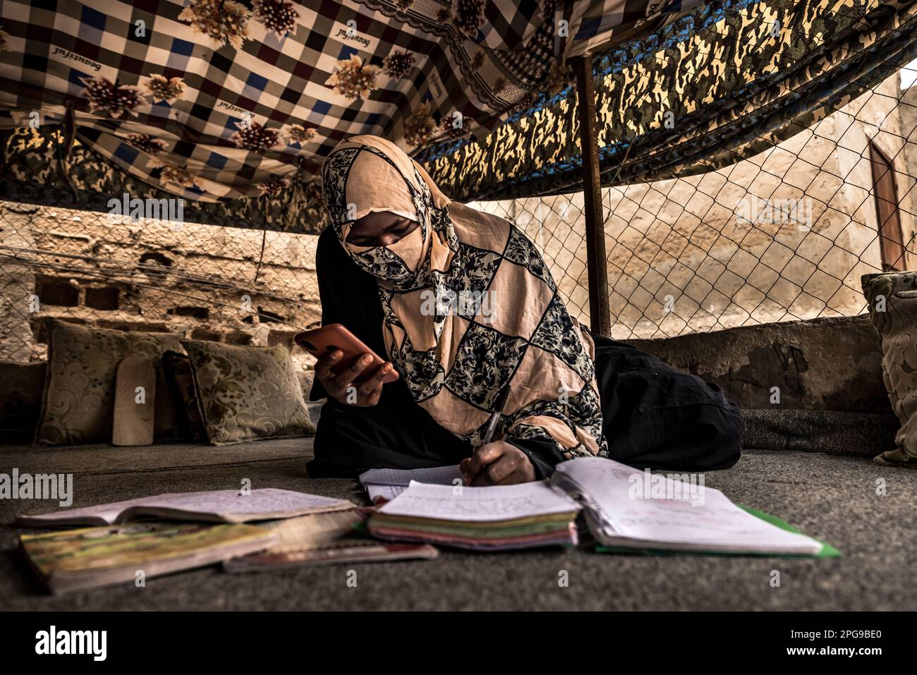 Schulmädchen, das in Nouakshott, Mauretanien, unter einem traditionellen Zeltdach neben dem Haus arbeitet, wo Mauretanier die heißen Sommermonate verbringen. Stockfoto