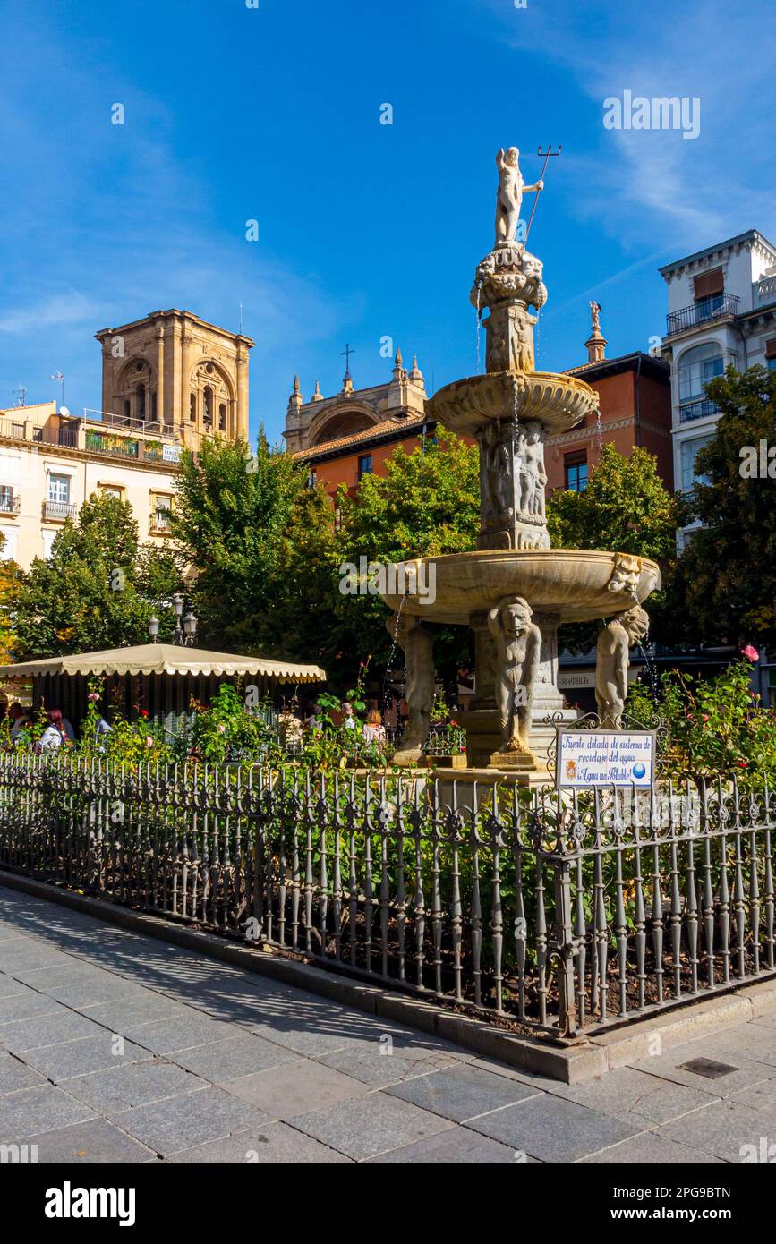 Brunnen auf einem öffentlichen Platz mit dem Dom-Turm im Hintergrund im Zentrum von Granada, einer Stadt in Andalusien, Südspanien. Stockfoto