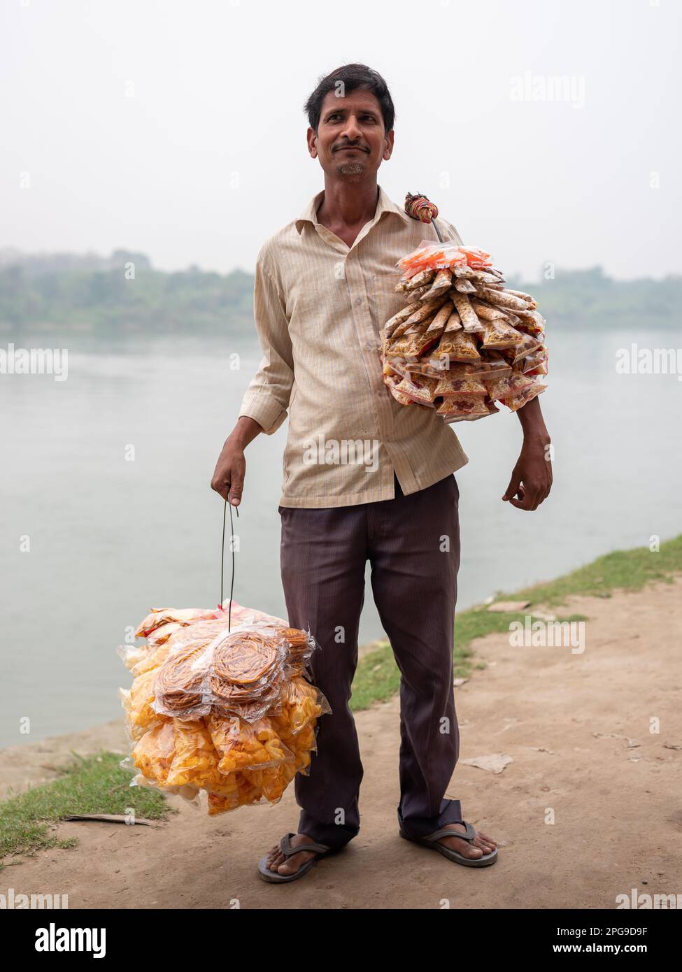 Ein Mann, der auf der Fähre über den Bhagirathi River in Murshidabad, Indien, verschiedene Leckereien verkauft. Stockfoto