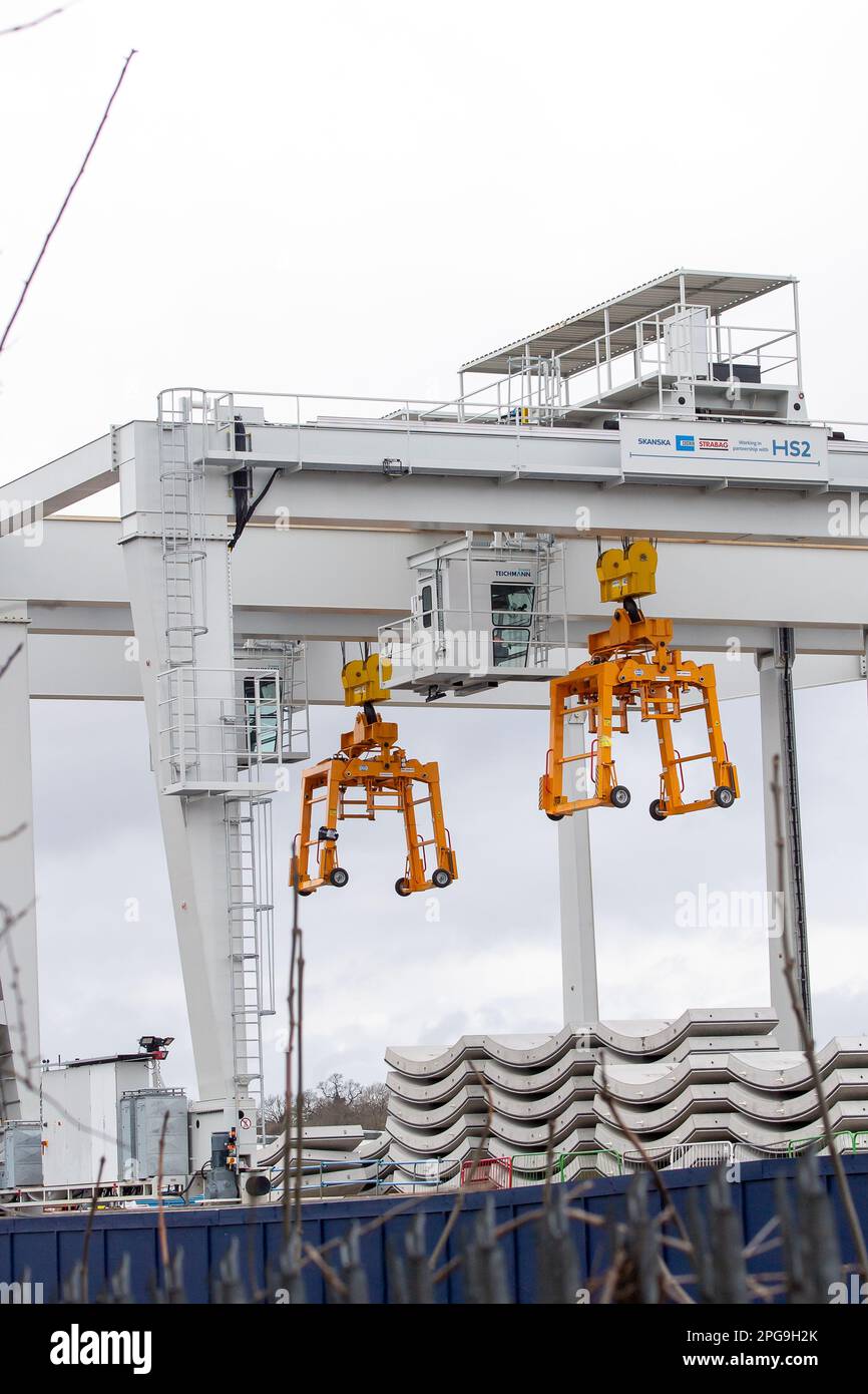 West Ruislip, Großbritannien. 21. März 2023. HS2 Bau von Hochgeschwindigkeitsbahnen in West Ruislip. Die Tunnelbohrmaschinen, die West Ruislip im Herbst auf dem Weg nach Euston in London verließen, haben Ruislip bereits einen Kilometer von ihrem Ausgangspunkt entfernt erreicht. Zwei benachbarte Tunnel werden unterirdisch von Tunnelbohrmaschinen (TBM) namens Caroline und Sushila gebohrt. Die Betontunnelsegmente wurden heute auf dem Gelände von HS2 West Ruislip von zwei 45-Tonnen-Kranen bewegt, die sich auf Rädern bewegen und sie anheben. Die Bewohner der Region haben Bedenken wegen einer Fülle von sprudelnder Flüssigkeit auf dem Rugby-Platz bei R geäußert Stockfoto