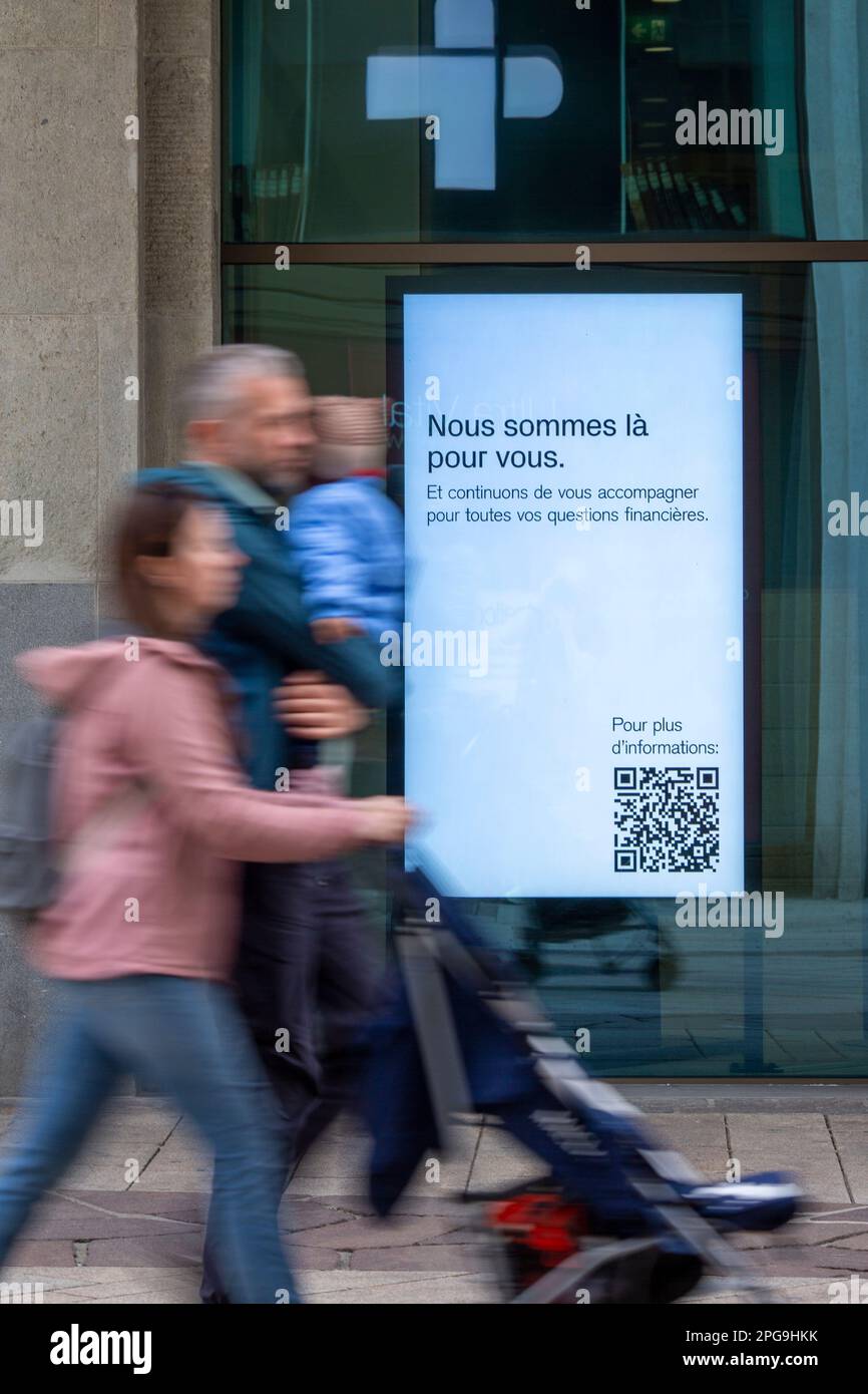 Schilder in den Fenstern der Hauptniederlassung der Credit Suisse in Genf zeigen die Meldung „Wir sind für Sie da“ an. Die Bank, die von ihrer konkurrierenden UBS übernommen wurde, um einen kaskadierenden Bankausfall zu verhindern, versucht nun, ihre Kunden zu beruhigen, die sich um ihr Geld sorgen. Stockfoto