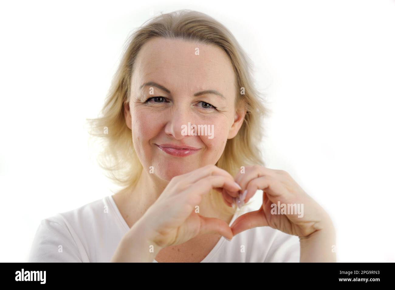 Glückliches Millennialmädchen, das die Hände am Herzen hält, fühlt sich dankbar, betet zu Gott am Arbeitsplatz, ruhige, friedliche junge Frau, die dankbar für Glück oder Schicksal ist, Glaube, Aberglaube, Dankbarkeit Stockfoto