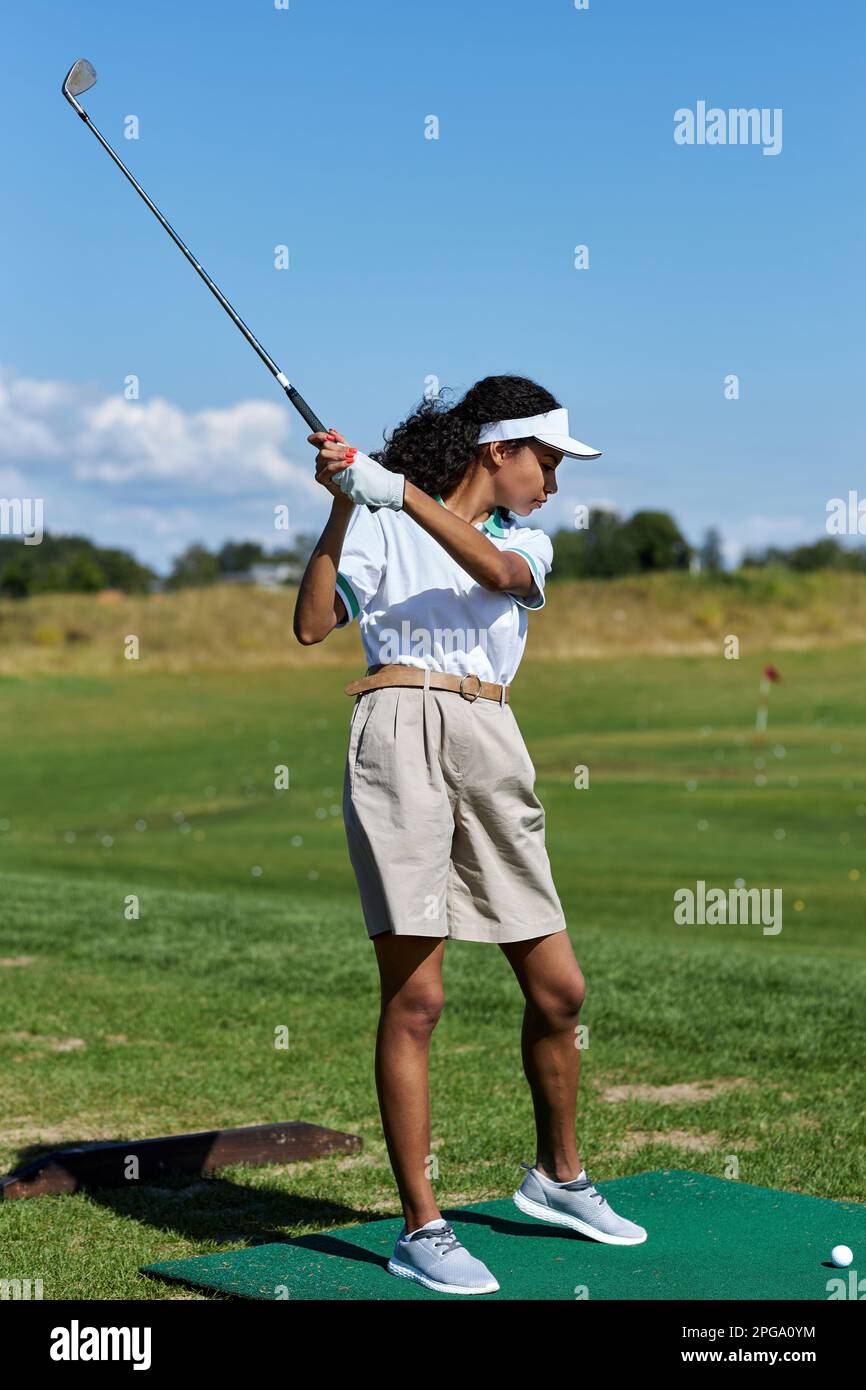 Vertikales, durchgehendes Porträt einer sportlichen Frau, die im Freien Golf auf grünem Gras spielt und einen schwingenden Golfschläger spielt Stockfoto