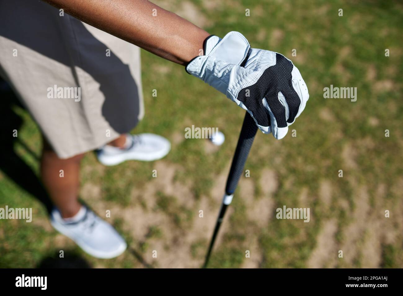 Nahaufnahme von oben: Weibliche Handschuhe, die den Golfschläger im Freien gegen Gras halten, Kopierbereich Stockfoto