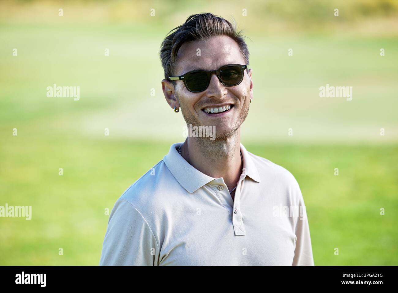 Porträt eines lächelnden Weißen mit Sonnenbrille im Sommer auf grünem Feld Stockfoto