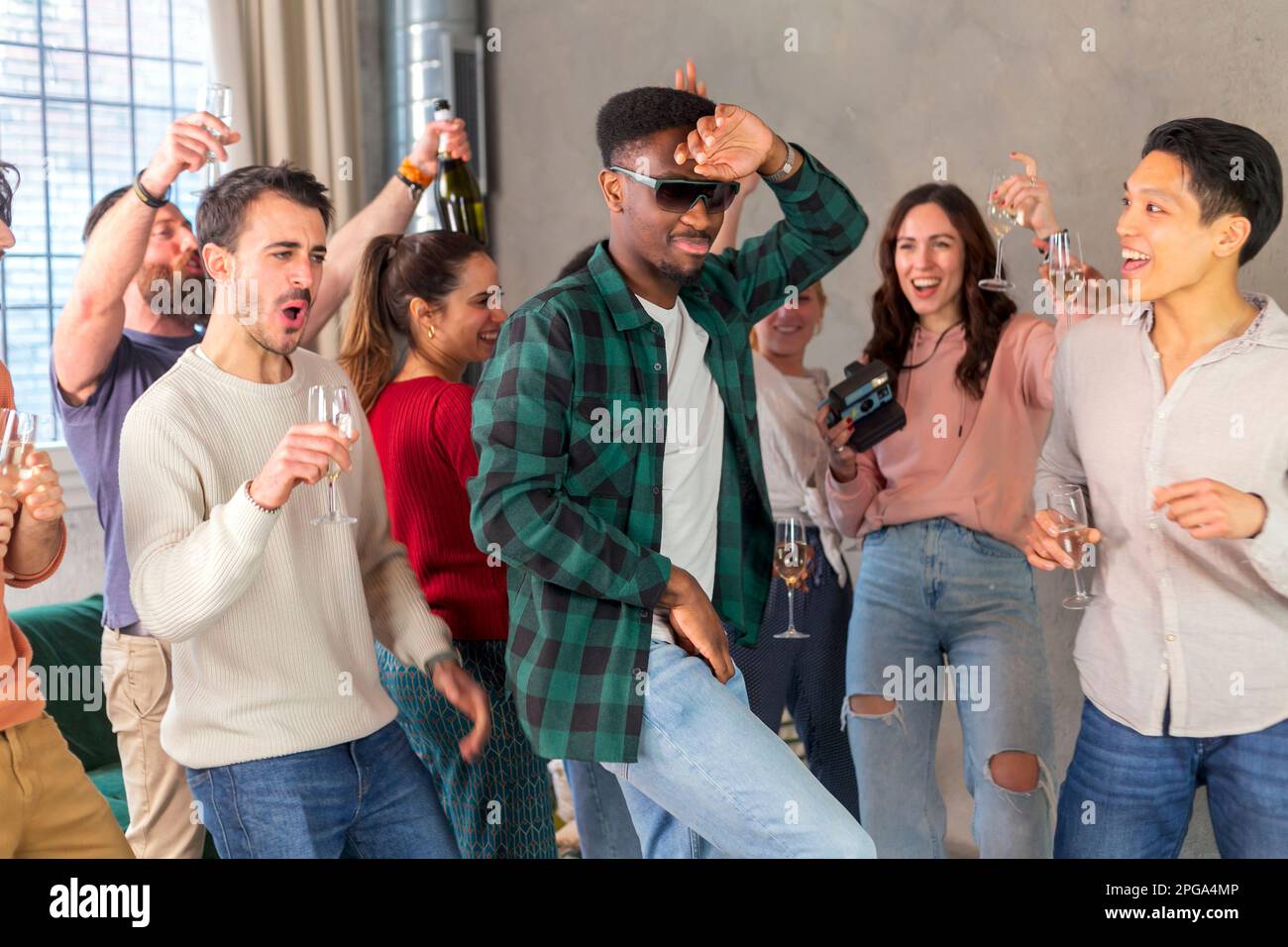 Multirassische Freunde tanzen und trinken Wein auf der Geburtstagsparty zu Hause Stockfoto