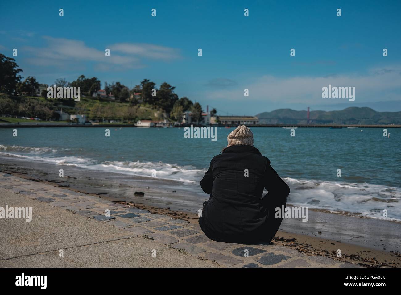 San Francisco, Kalifornien, USA. 20. März 2023. Die Leute sitzen am Strand am Ghirardelli Square und genießen einen wunderschönen Blick auf die Bucht von San Francisco und das Meer dahinter. Der Ghirardelli Square in San Franciscos berühmtem Viertel Fisherman's Wharf ist ein historisches Wahrzeichen, das seit über 50 Jahren Einheimische und Touristen gleichermaßen begeistert. Der Platz wurde 1893 als Hauptsitz der Ghirardelli Chocolate Company erbaut und wurde im Laufe der Jahre mehrfach renoviert und verändert. Er ist jedoch weiterhin ein beliebtes Ziel für Shopping, Restaurants und Unterhaltung. (Credi Stockfoto