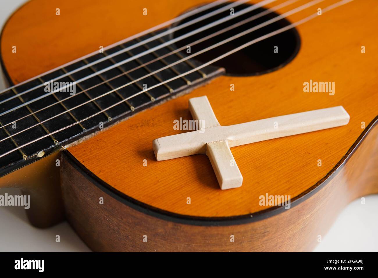 Akustikgitarre mit Holzkreuz auf dem Tisch, Nahaufnahme. Christliche Musik. Stockfoto