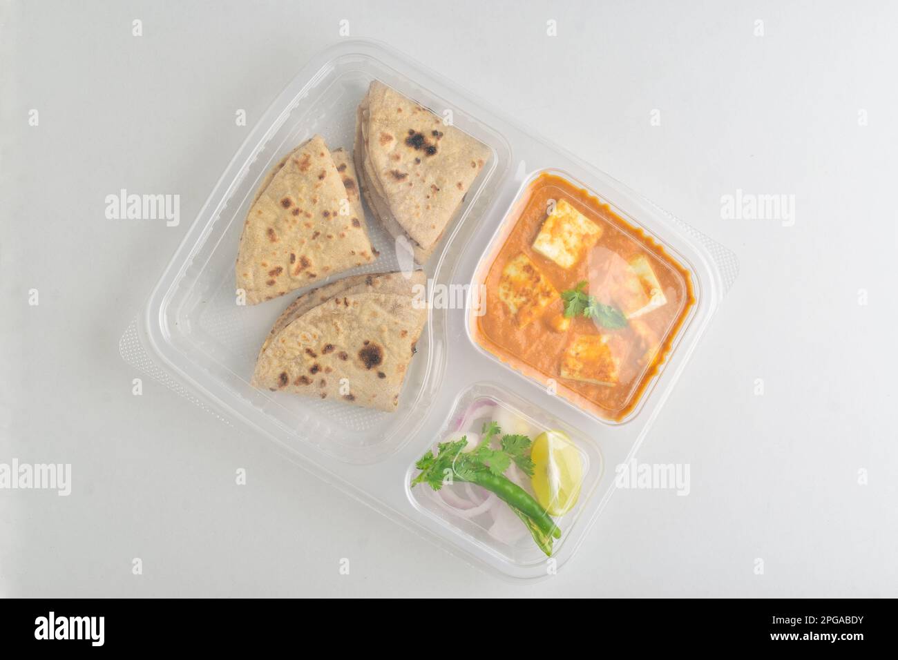 Abgepackte indische Mahlzeit isoliert auf weißem Hintergrund, shahi-Paneer mit tawa Roti und Salat in Einwegtellern Stockfoto