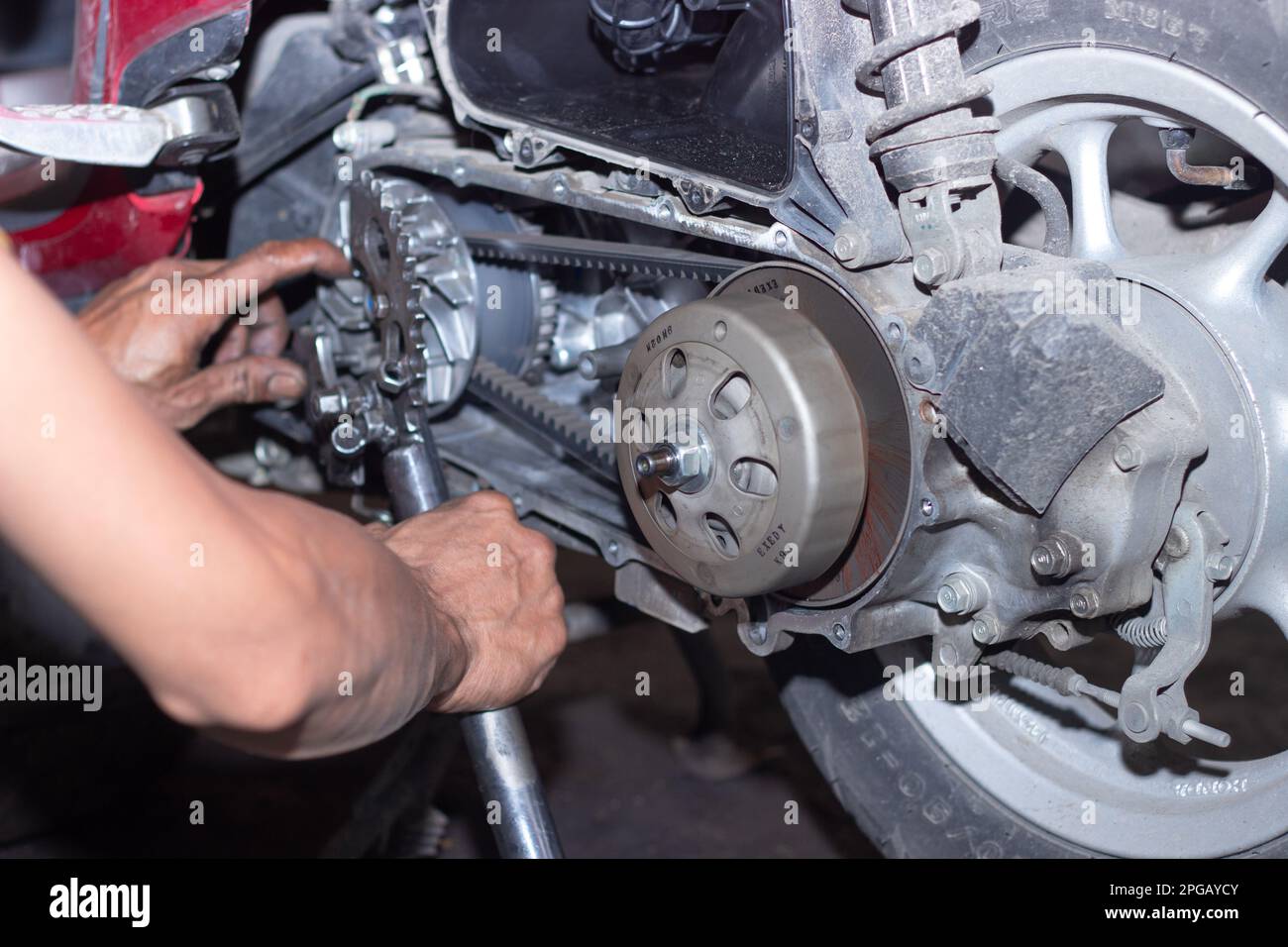 Der Motorradmechaniker prüft den Zustand des Automatikgetriebesystems oder des Kupplungssystems des Rollers in der Werkstatt. Reparatur und Wartung Motorradkonzept Stockfoto