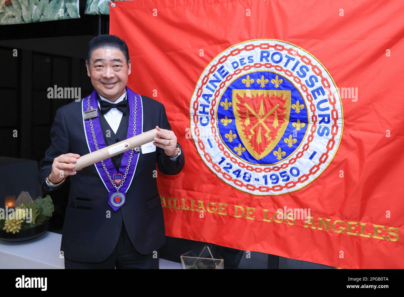 West Hollywood, Kalifornien, USA. 19. März 2023. Der Fernsehmoderator Joey Zhou hält eine U-Bahn mit einem Zertifikat im Inneren bei der Einführungszeremonie in Los Angeles und Beverly Hills Bailliage im Boxwood Restaurant im London West Hollywood Hotel in West Hollywood, Kalifornien. Kredit: Sheri Determan Stockfoto