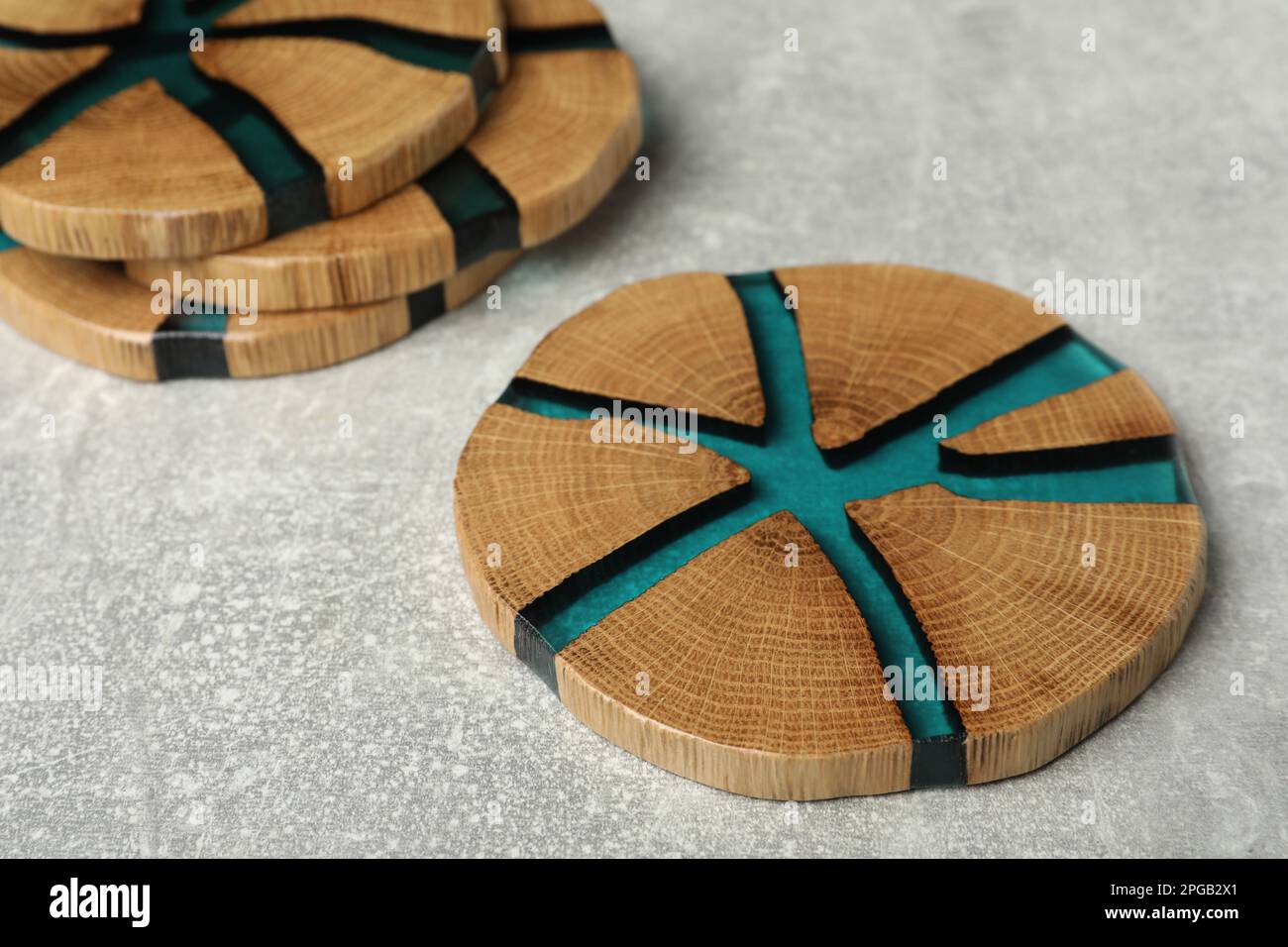 Stilvolle Untersetzer mit Holzbechern auf hellgrauem Tisch Stockfoto