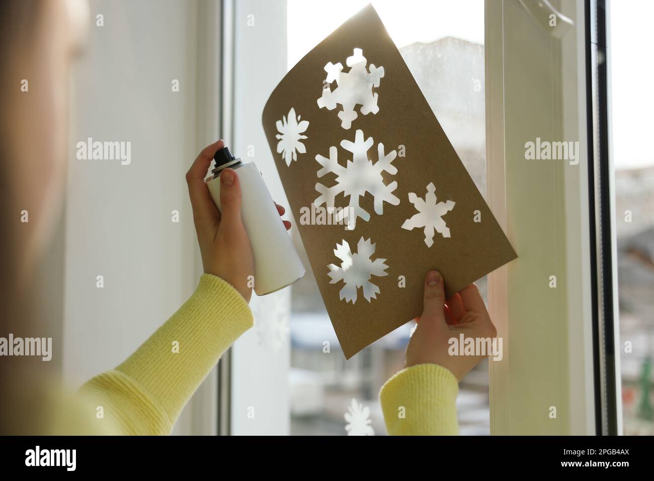 Eine Frau, die Schneespray benutzt, um zu Hause Fenster zu