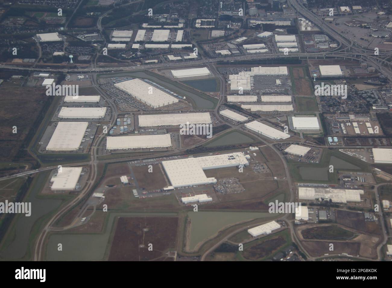 Von oben erstreckt sich der weitläufige industrielle Lagerhauskomplex mit Reihen von Metalldächern und Laderampen so weit das Auge reicht. Stockfoto