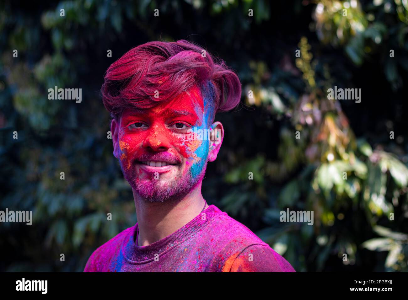 Ein junger Indianer, dessen Gesicht mit bunten Pulvern bestrichen war, während des Hindufestivals von Holi, Stockfoto