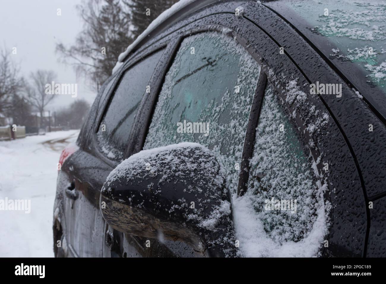 Frischer Schnee bedeckt die Umgebung und den Autospiegel, Schneetextur auf einer Metalloberfläche, Winter. Stockfoto