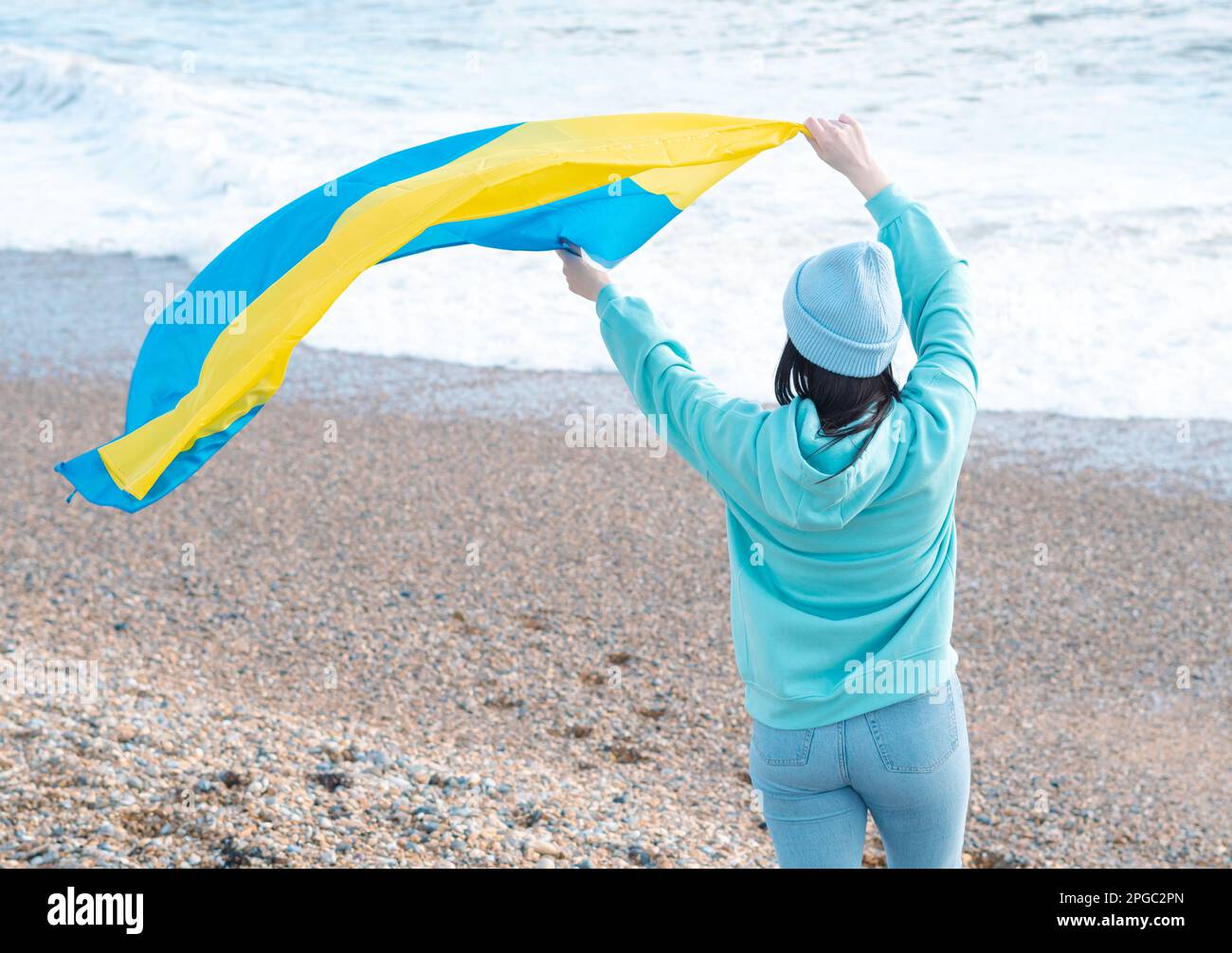 Braune Frau in blauem Hoodie und blauem Hut mit ukrainischer Nationalflagge, patriotisches Konzept Stockfoto