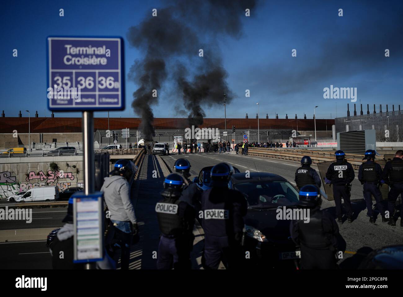 Dock workers face riot police as they stand in front of a burning ...