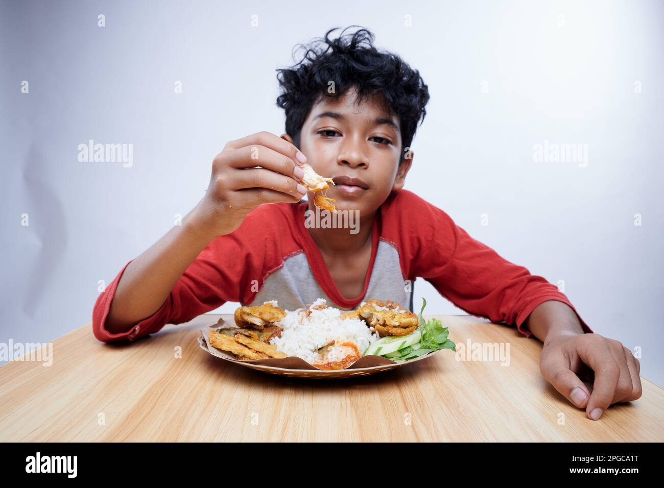 Ein Kind isst gebratenes Hühnchen und Reis zum Mittagessen Stockfoto